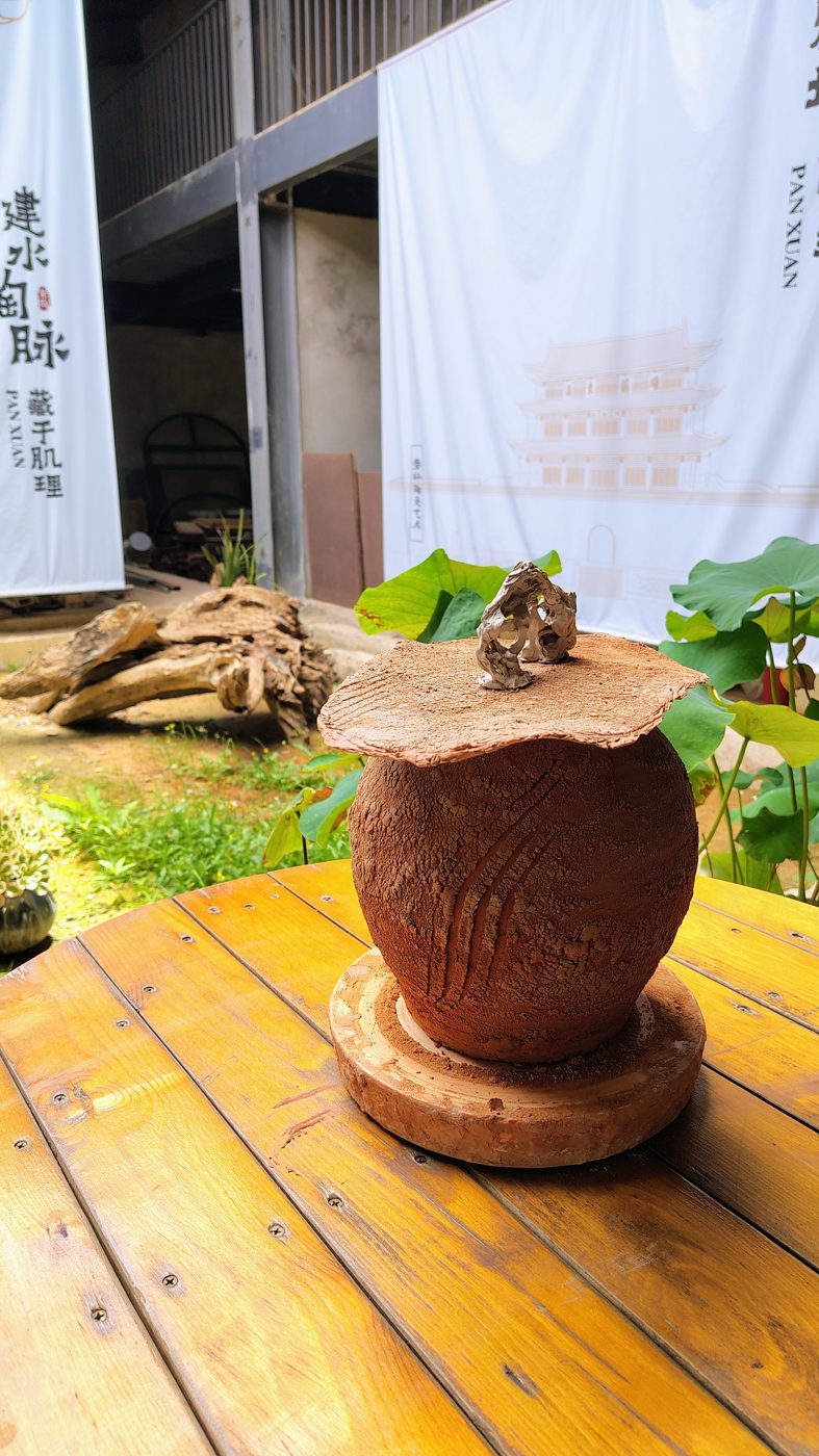 A piece with a clay-slab lid between the lotus plants
